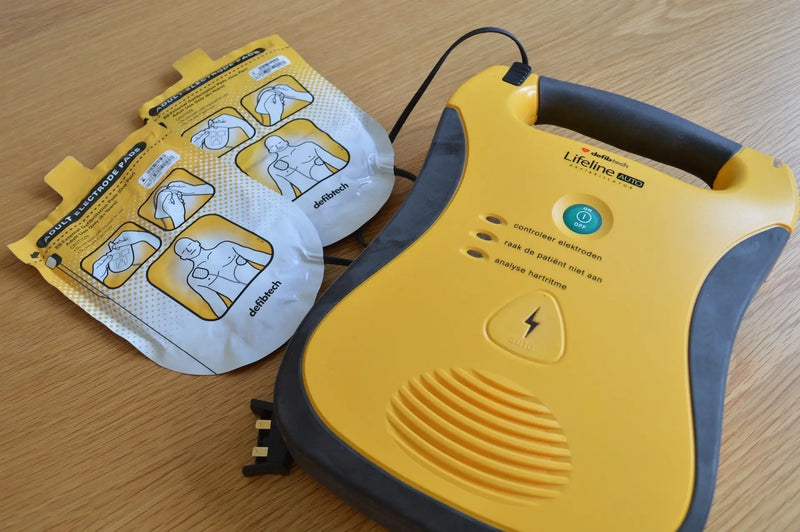 Yellow and gray automated external defibrillator with electrode pads.