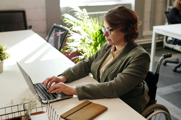 Woman in wheelchair using laptop.